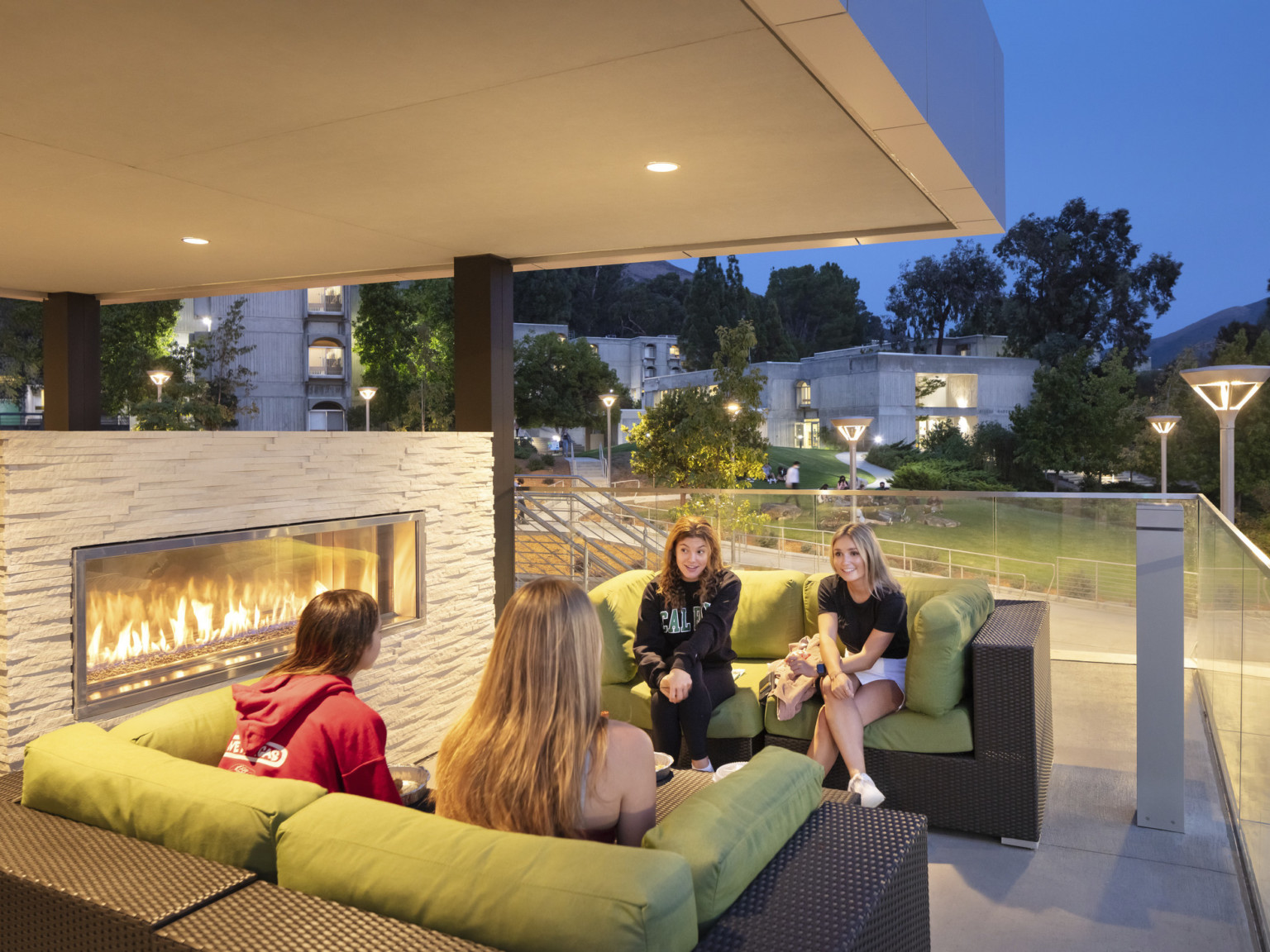 Outdoor seating area with couches facing each other at corner of balcony next to stone fireplace, all covered by overhang