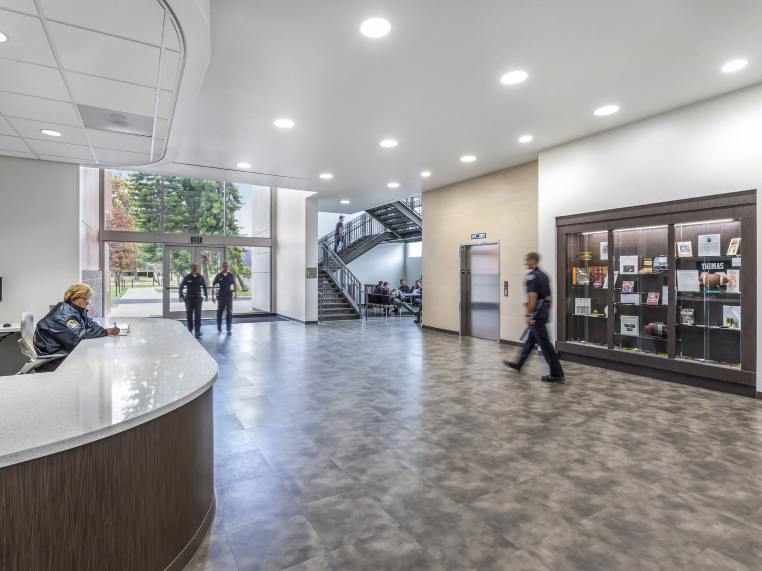 White ceiling with recessed lighting over entrance and reception desk with view to glass double doors.