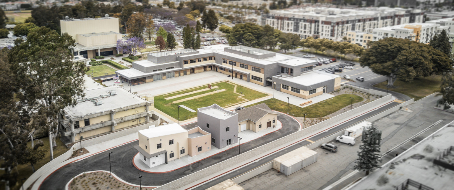 Aerial view of multi building complex from the rear with field at center