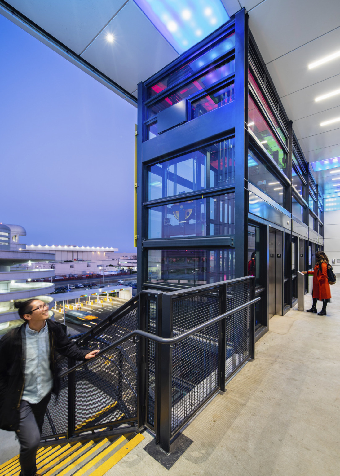 Garage interior from the top of stairs left of colorful glass tower containing elevator shafts