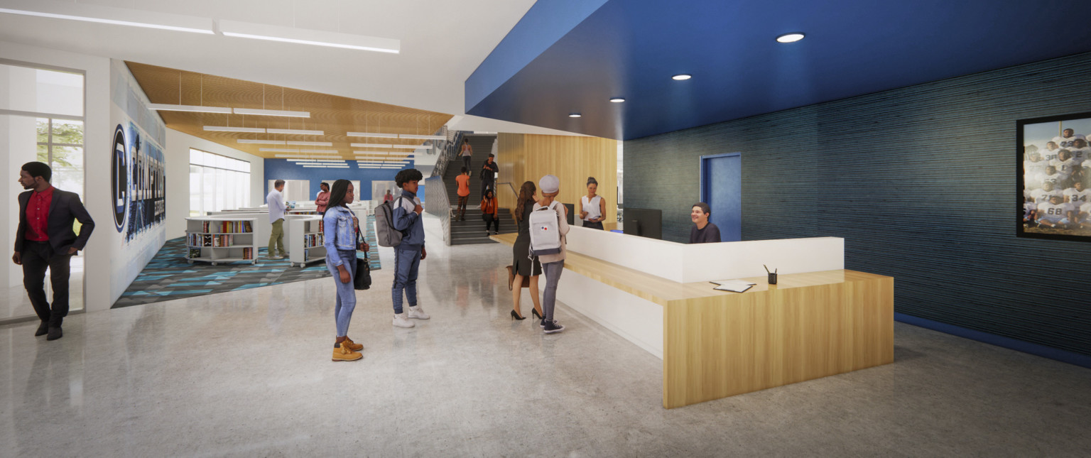 Wood reception desk with white partition sits under a blue drop ceiling accent with recessed lighting. Beyond are bookshelves