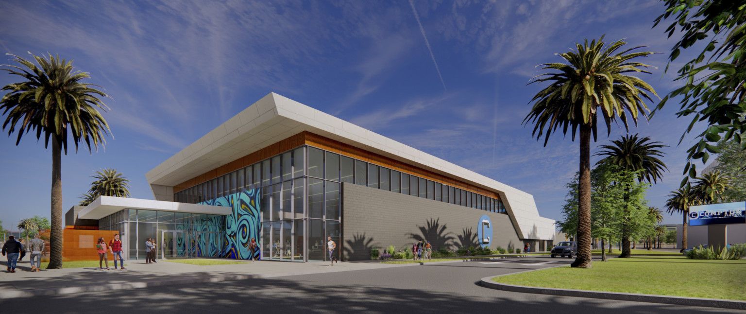 Building entry with double height windows and grey wrapping facade to right. White roof with overhang and wood details