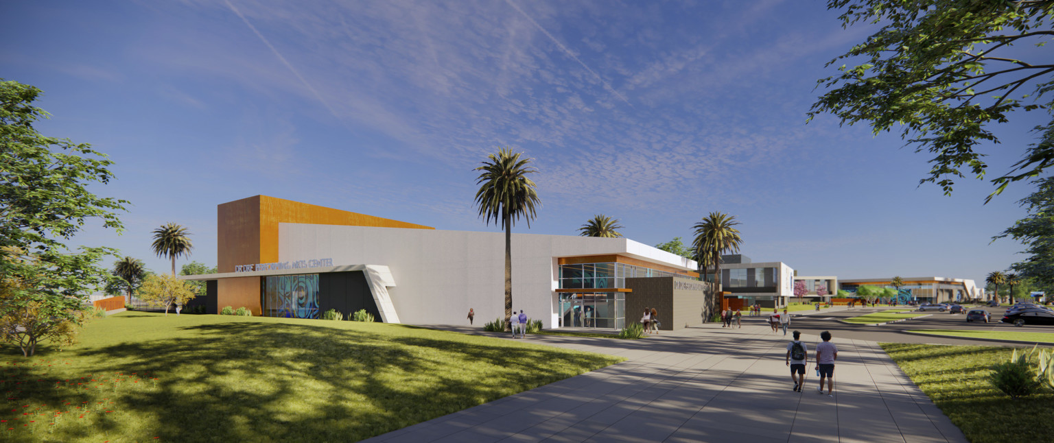 Corner view of building labeled Dr Dre Performing Arts Center. Angled white wrapped facade with brown details and mural left