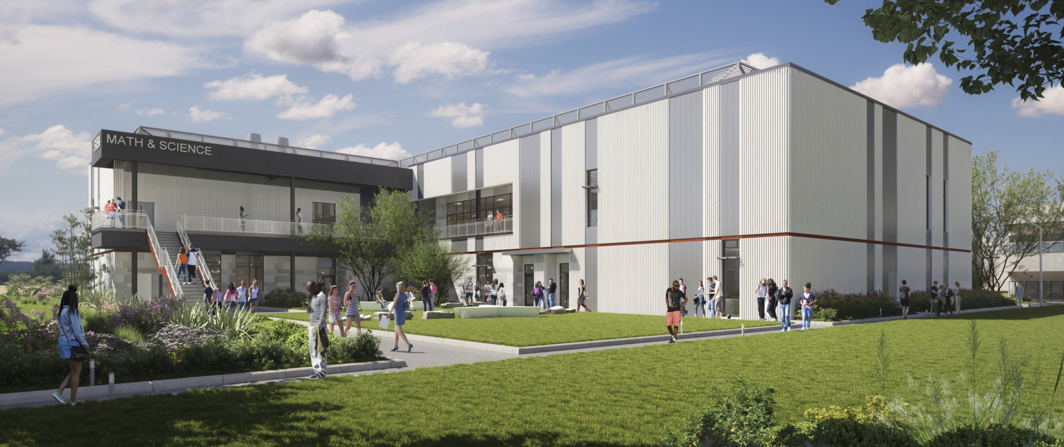 View of building across courtyard. Grey siding with red stripe detailing between floors. Stairs right to 2nd floor walkway