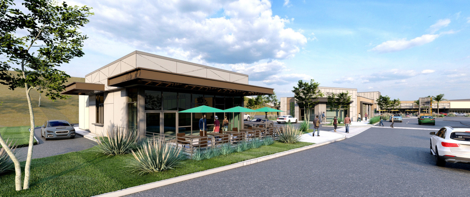 Native plants line partially covered outdoor patio of restaurant with floor to ceiling windows and a drive through on left