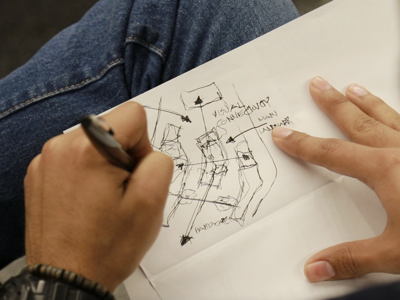 Close up view of student sketching a site plan with labeled arrows