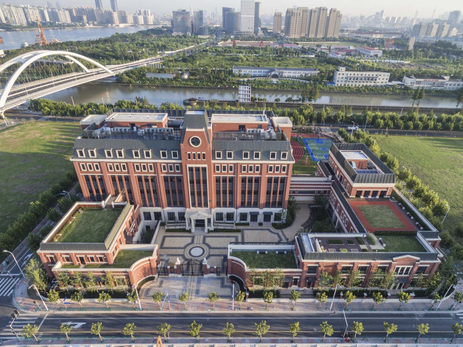 Aerial view of the campus from the front. A gated stone courtyard is surrounded by brick buildings with living roof sections