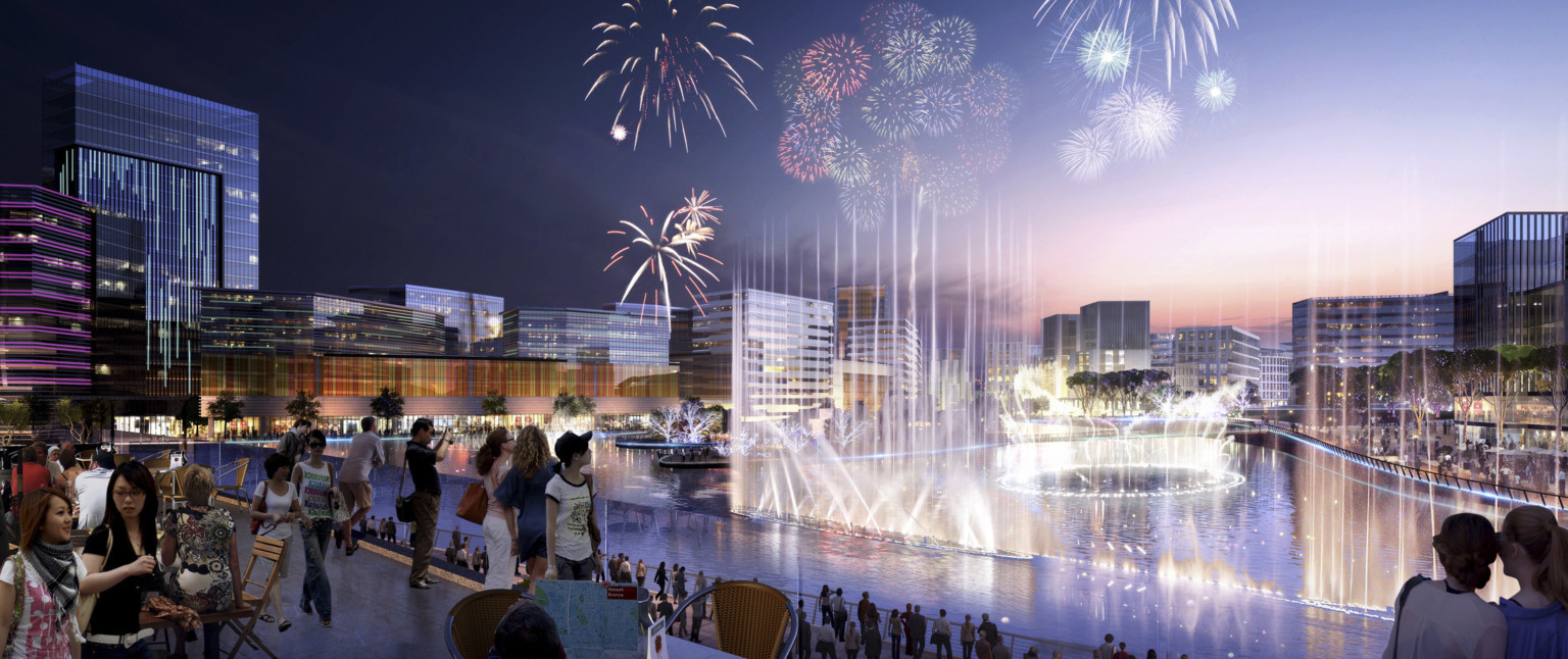 Tree lined lake with fountains surrounded by multistory glass buildings in the evening with fireworks overhead