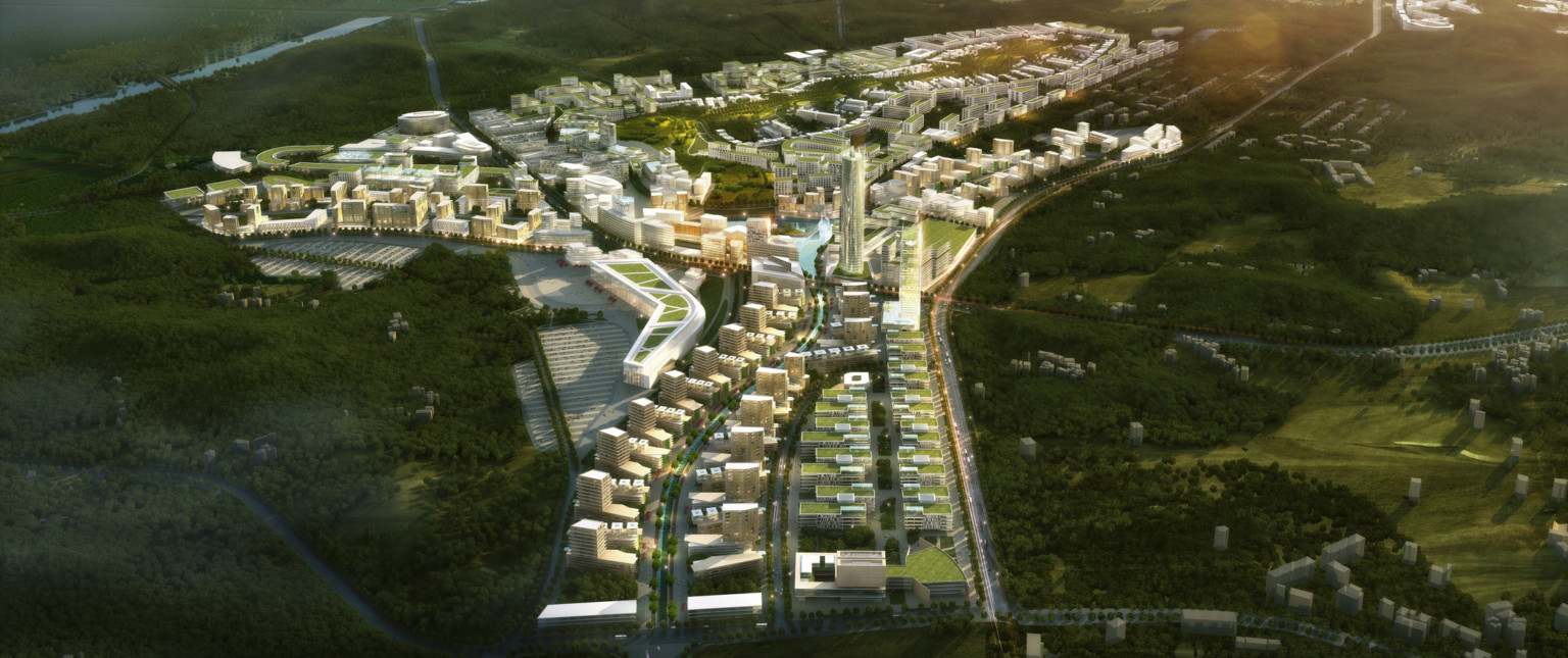 Aerial view of city with green roof multistory buildings and tall cylindrical tower surrounded by green hills