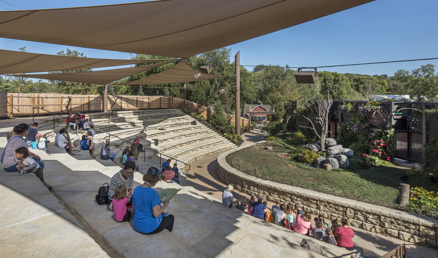 Partially covered organic rock bleacher seating curving to face stage with grass and trees