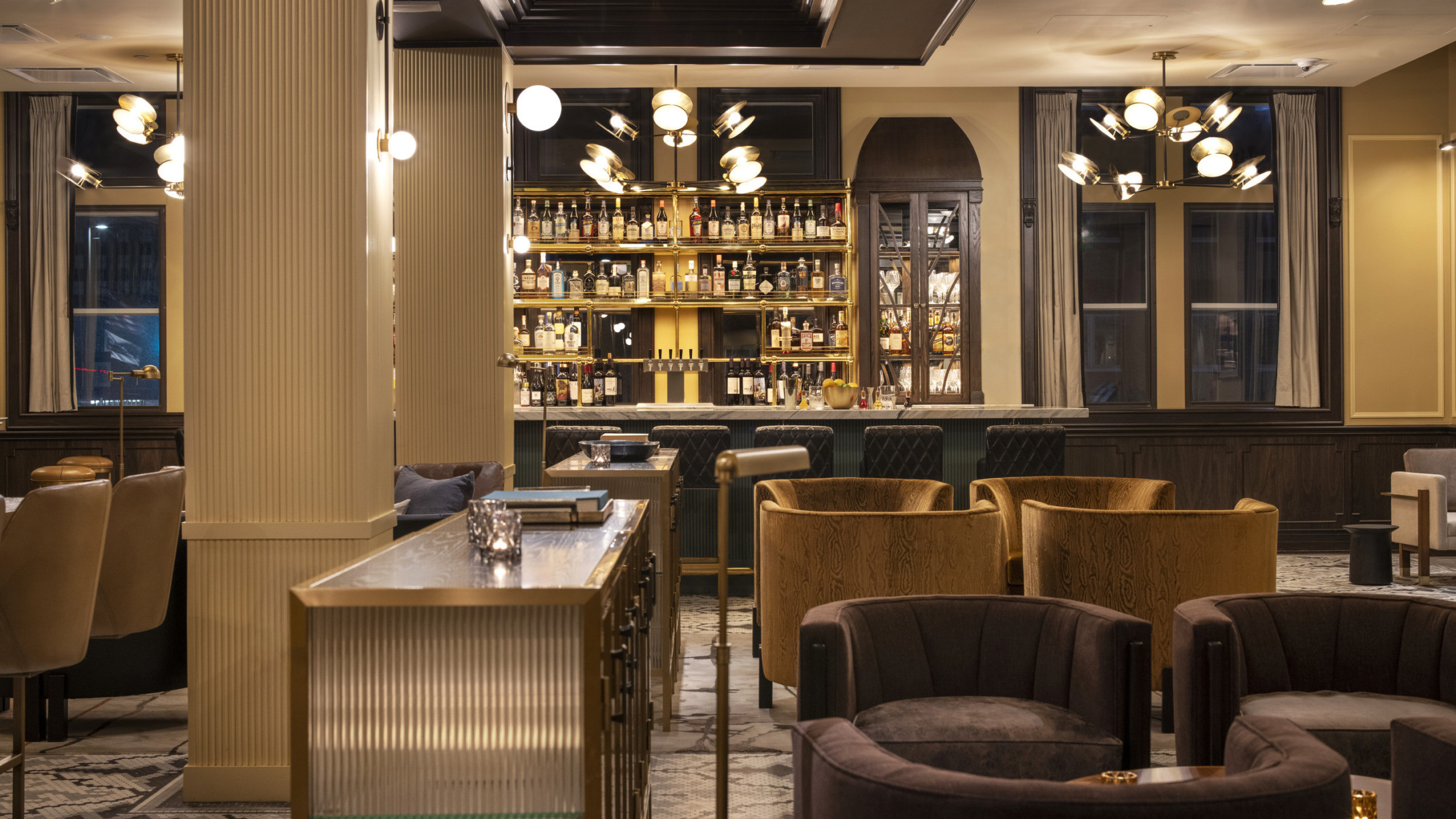 Kimpton Cottonwood Hotel lobby with velvet upholstered seating area in front of marble counter bar. Chandelier light fixtures
