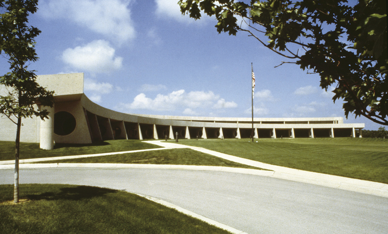 Exterior of Central States Health and Life Insurance Building, a curved concrete building on green lawn with American flag