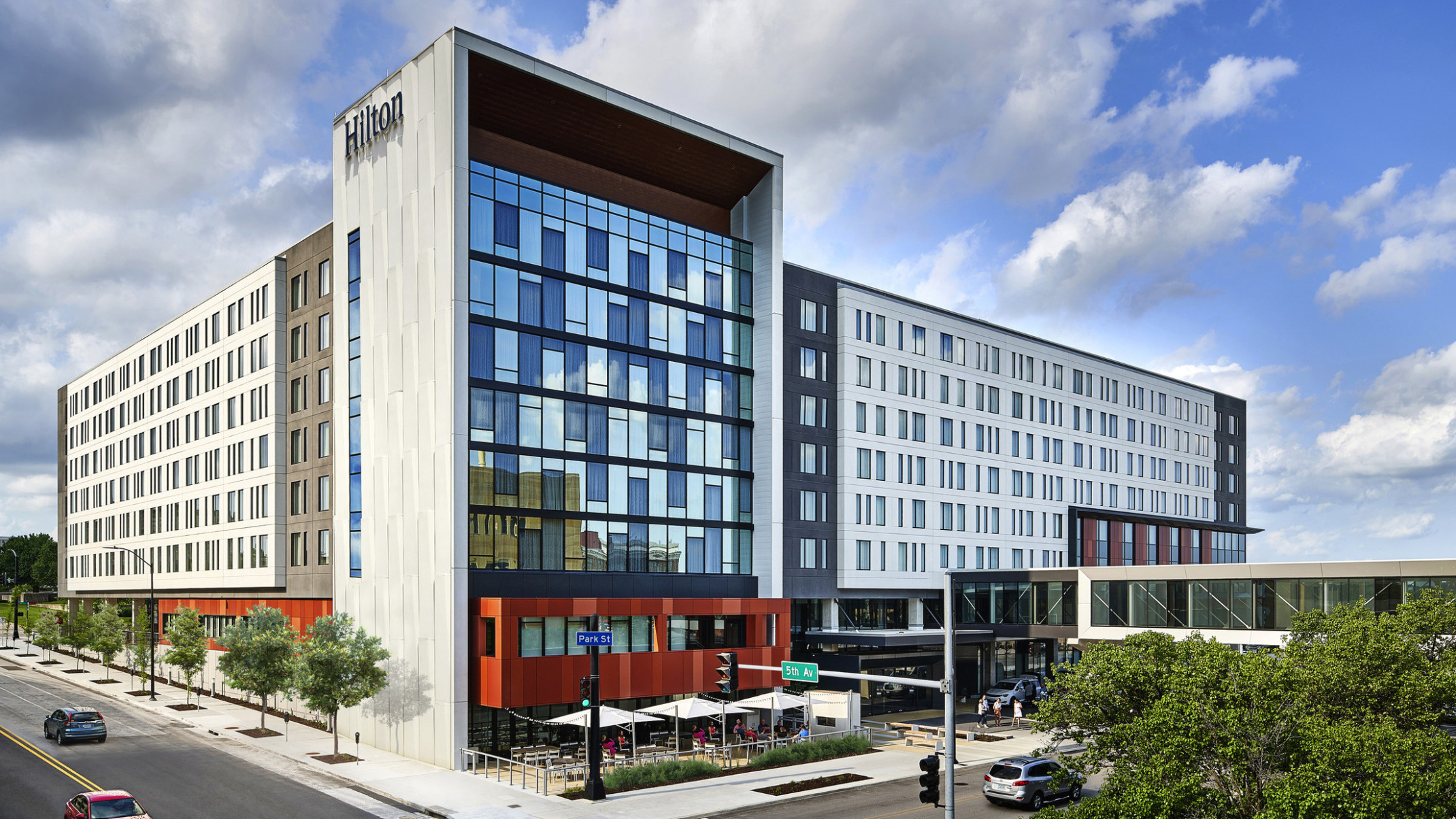 Hilton Des Moines Downtown hotel seen from the front corner. Window front wall shaded by extended white wall with Hilton sign