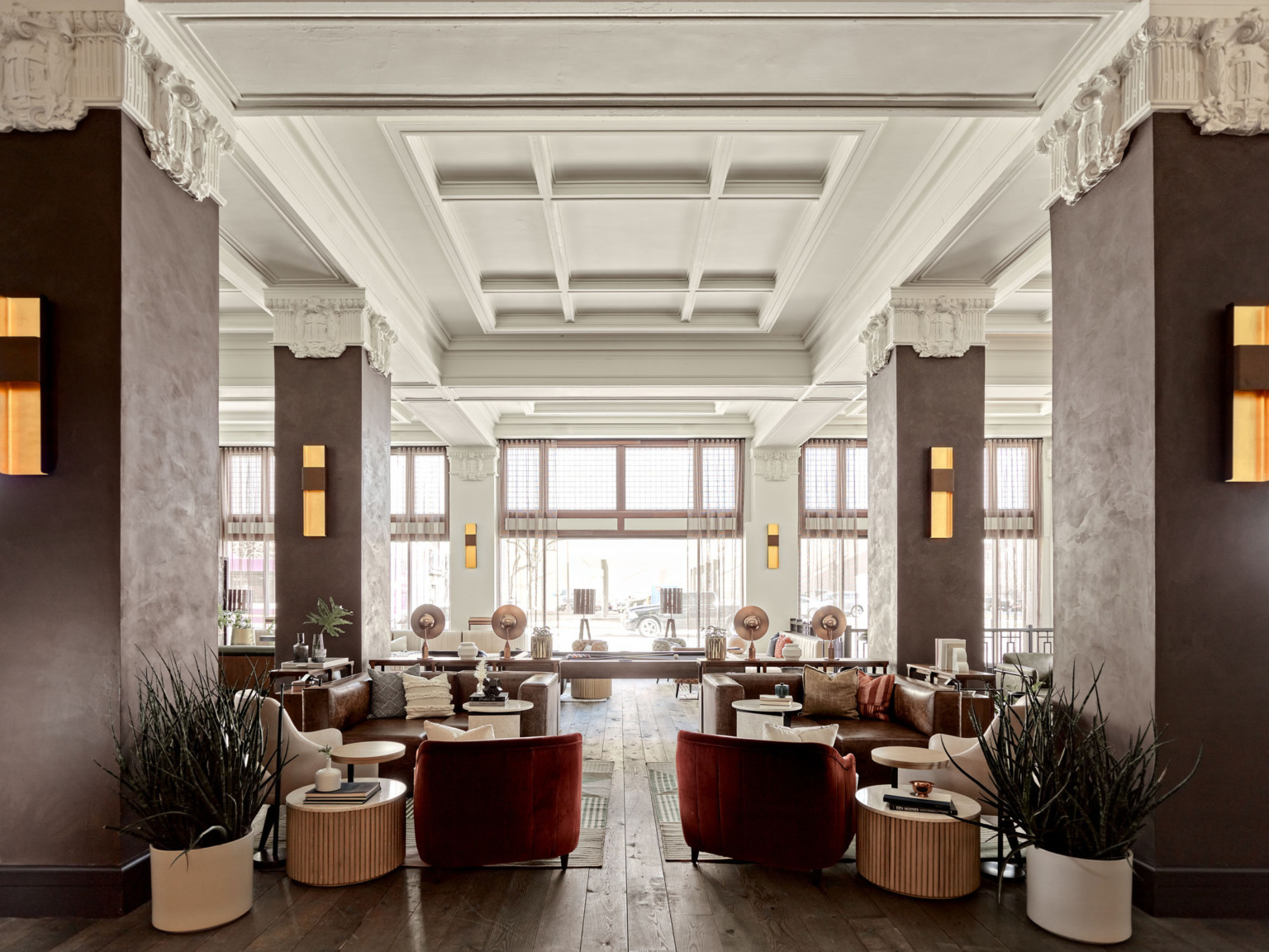 Seating area in the with wood pillars and white stone capitals in white room with recessed ceiling details. Pool table center