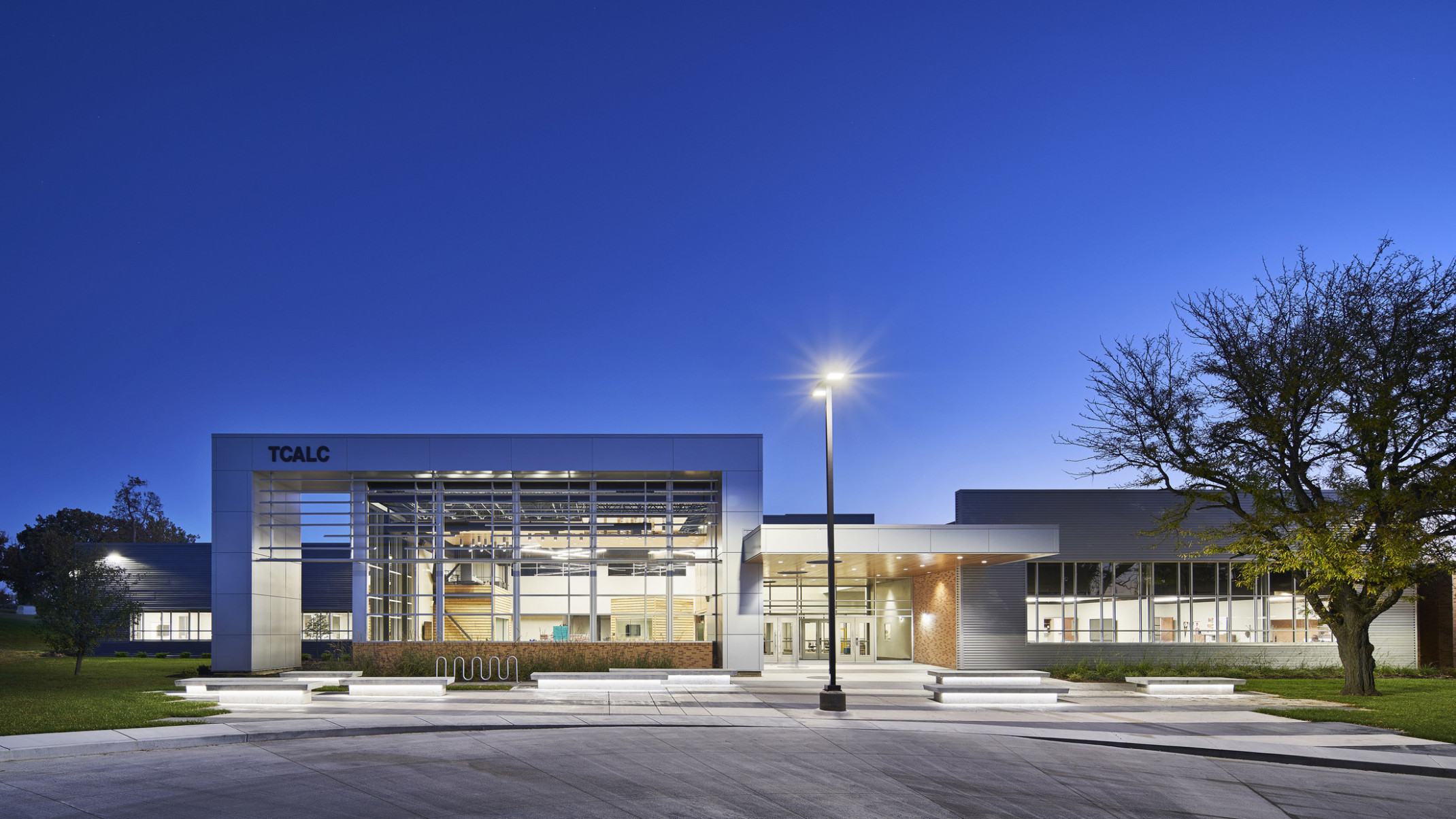 evening exterior view of school with floor to ceiling windows and lighting at Topeka Center for Advanced Learning & Careers