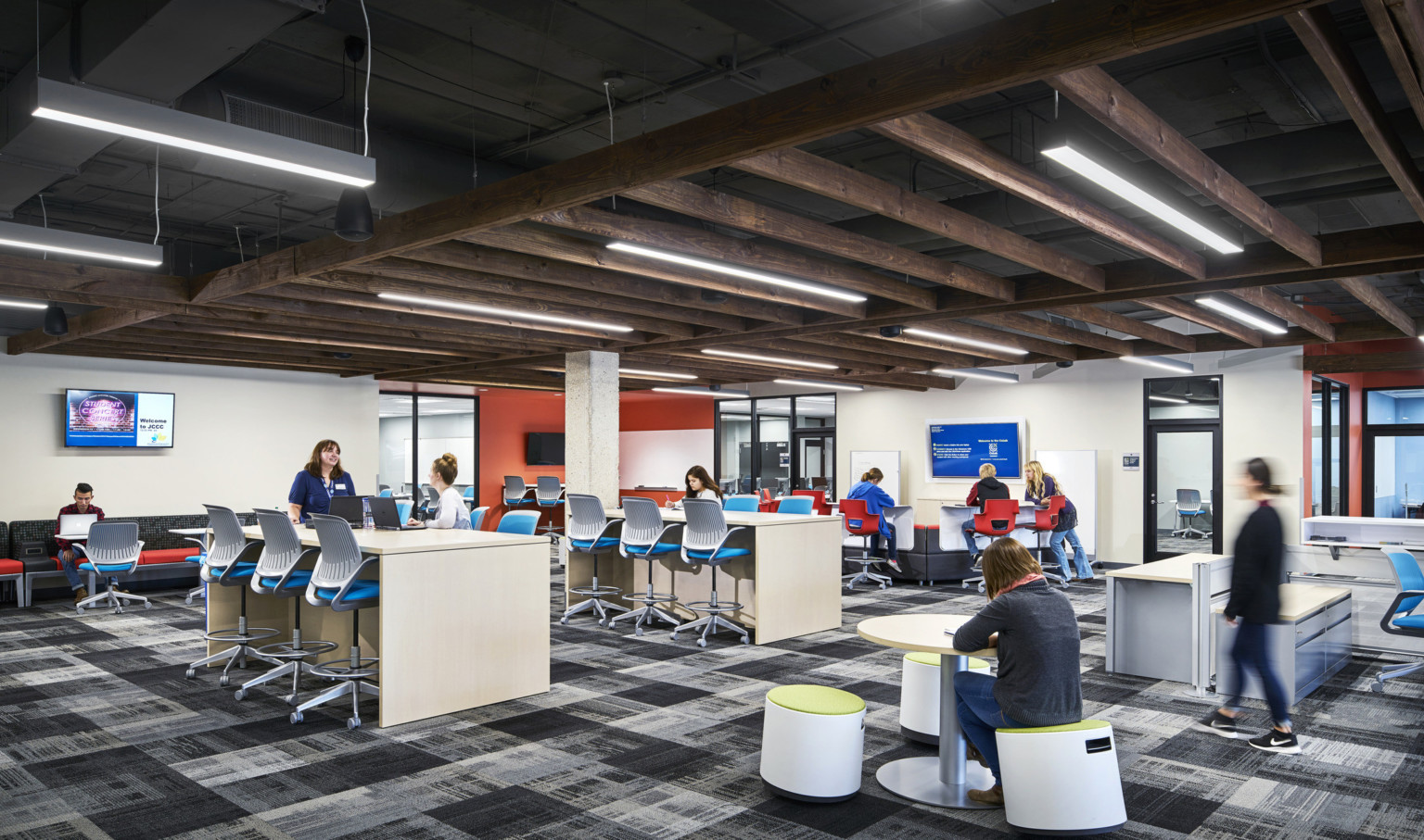 multiple student collaboration areas with flexible seating under wood panel drop ceiling accent in white room with screens