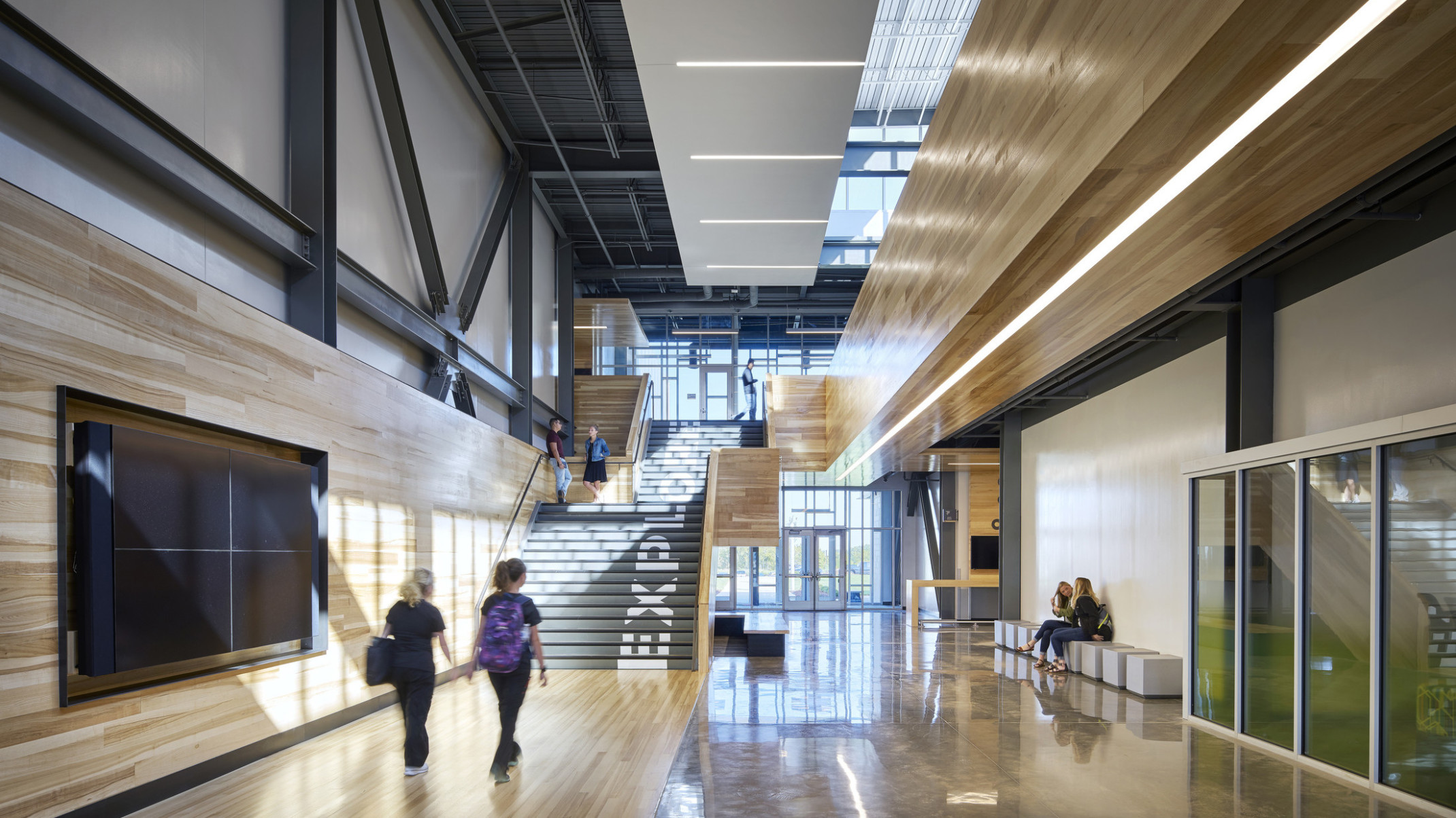Missouri Innovation Campus interior hallway facing double height glass windows at entry and black staircase with wood walls