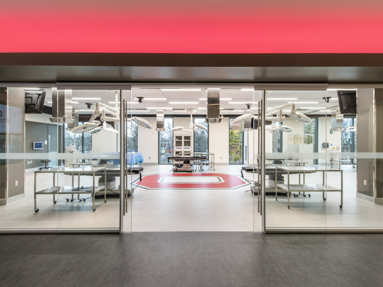 Room in the Jameson Crane Surgical Skills Lab with beds with circular lights suspended above, a large red O on floor center