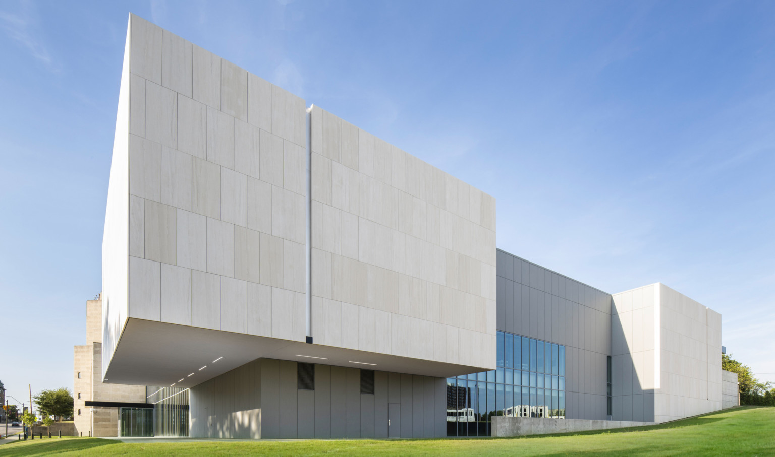 Exterior view of back corner of concrete building, built along a green grass hill