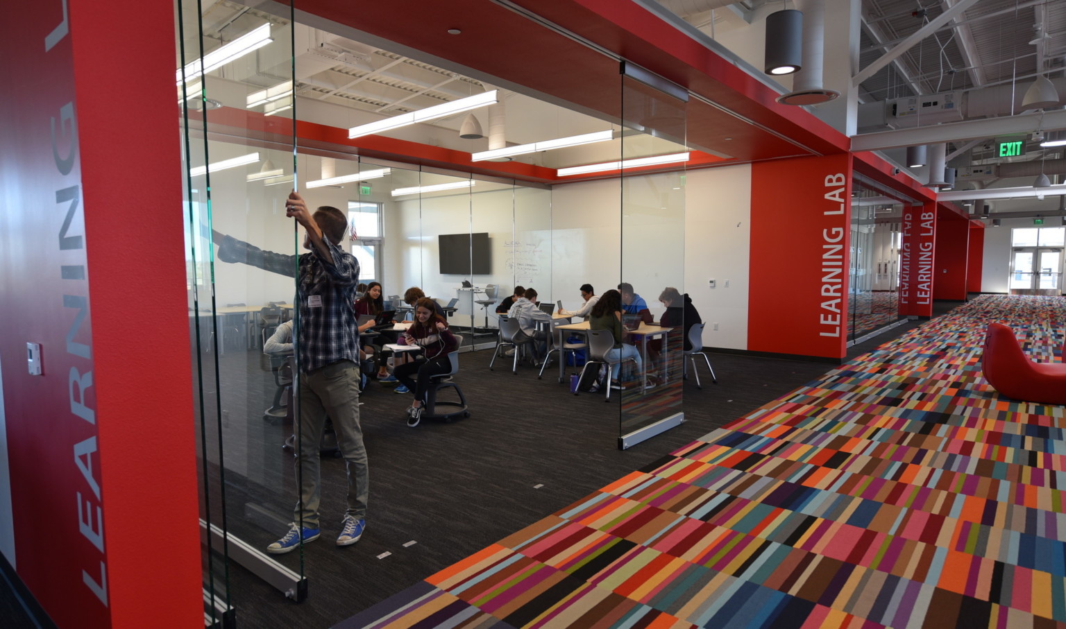 a movable glass wall and bright multi colored carpet in a learning environment