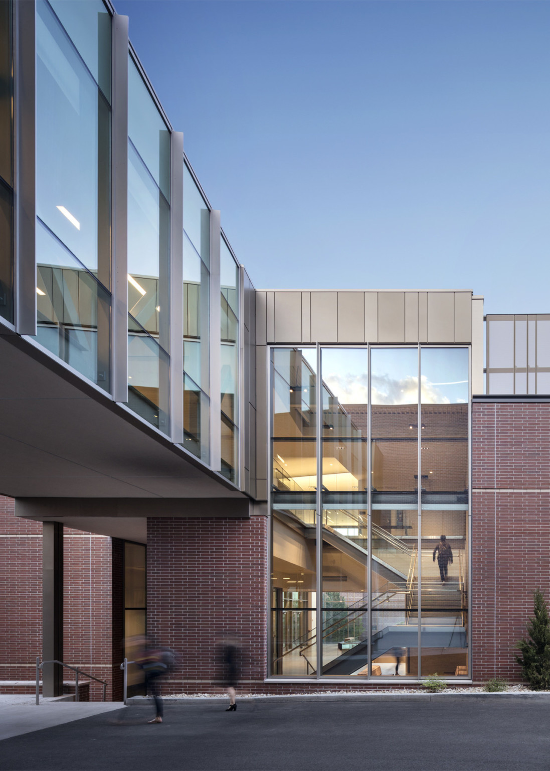 A skywalk connecting to a brick building with double height window looking into stairs