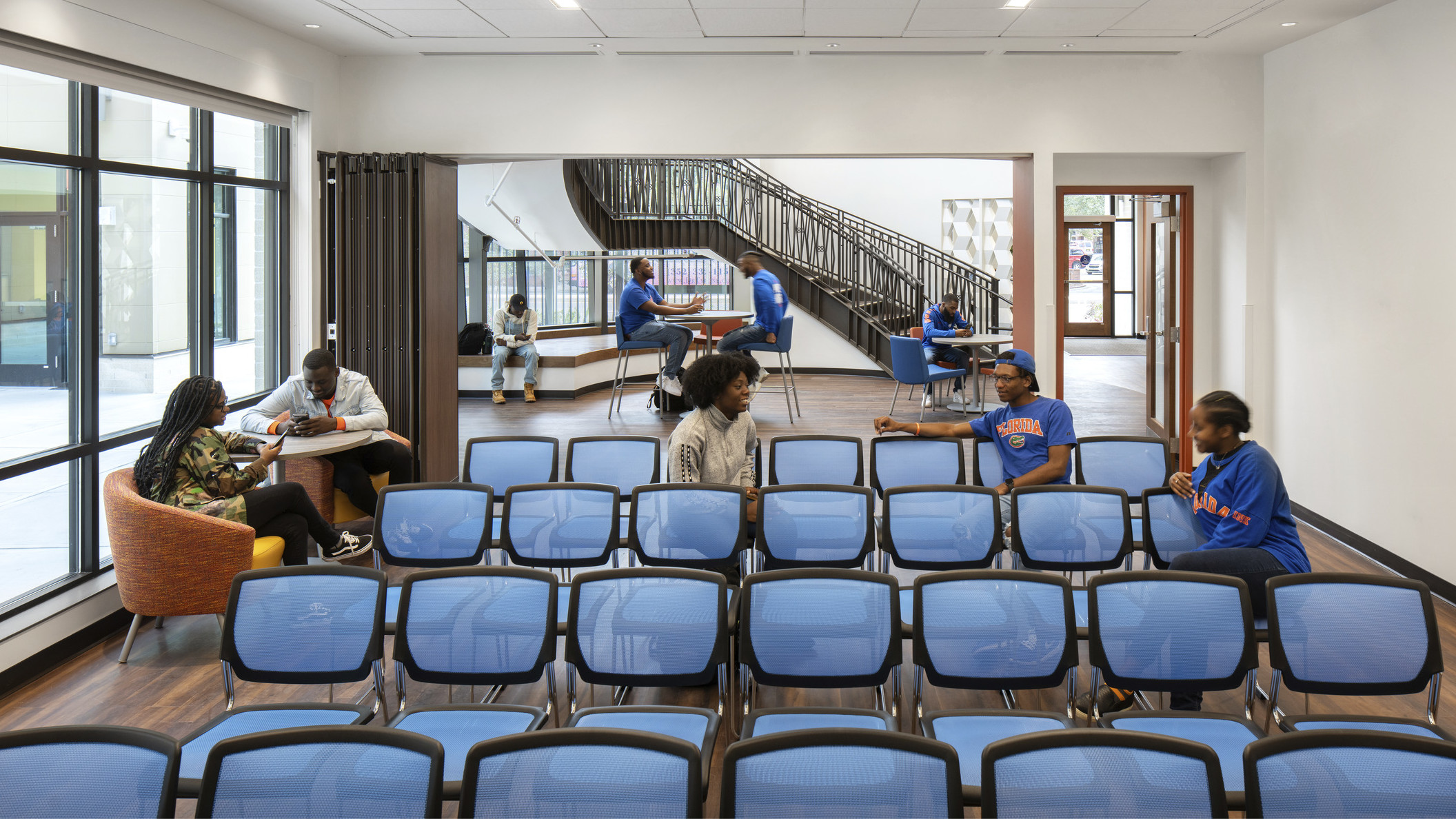 Off the main lobby with high tables and chairs, a room with flexible wall and chairs facing forward. More seats near windows