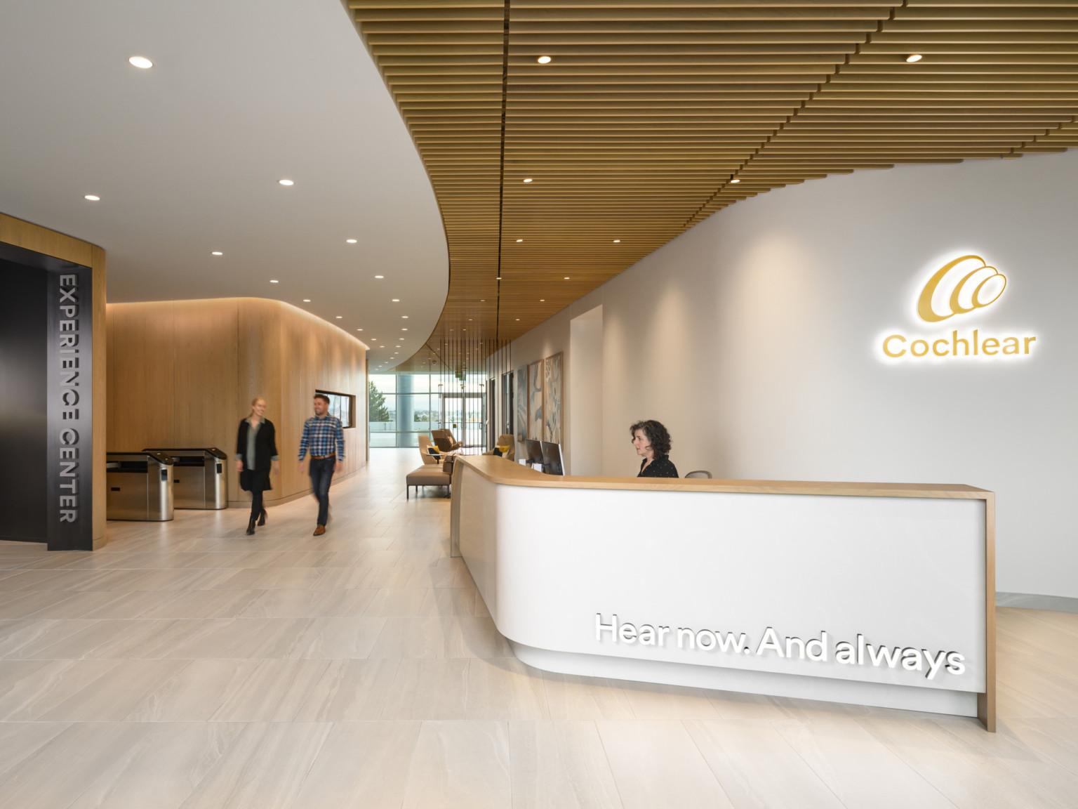 Cochlear North American Headquarters entrance with white reception desk in front of backlit logo with wood ceiling accents