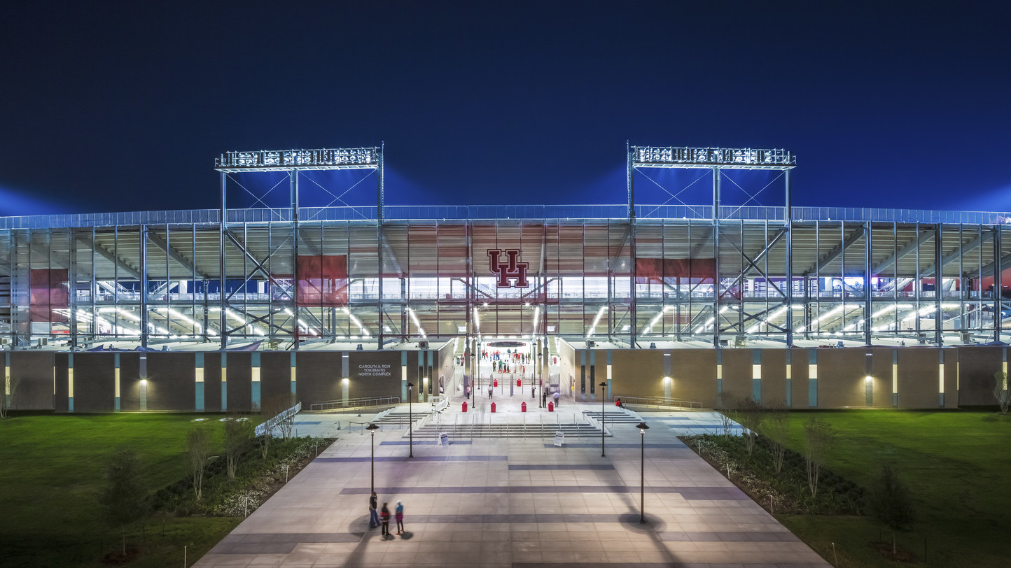 TDECU Stadium at University of Houston front entrance illuminated at night. Red UH logo over entry