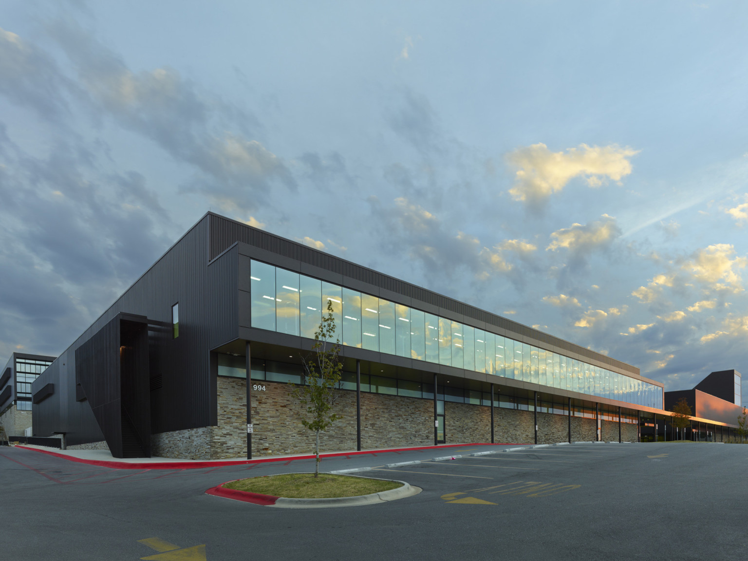 Fayetteville High School 2nd floor with seamless window hallway extends to create covered walkway above stone wall to entry