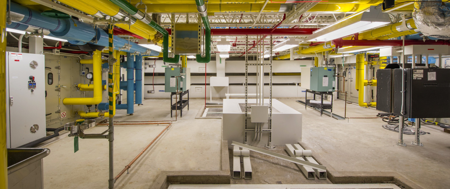 Colorful exposed pipes in white room with mechanical boxes