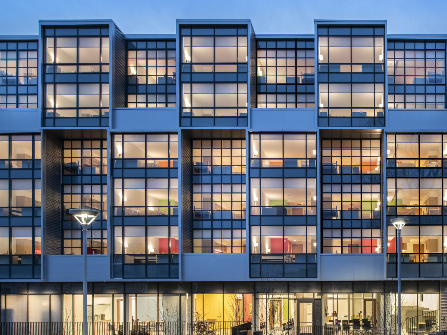 Exterior view of a section the Triumph with window covered facade illuminated at night with interior rooms visible