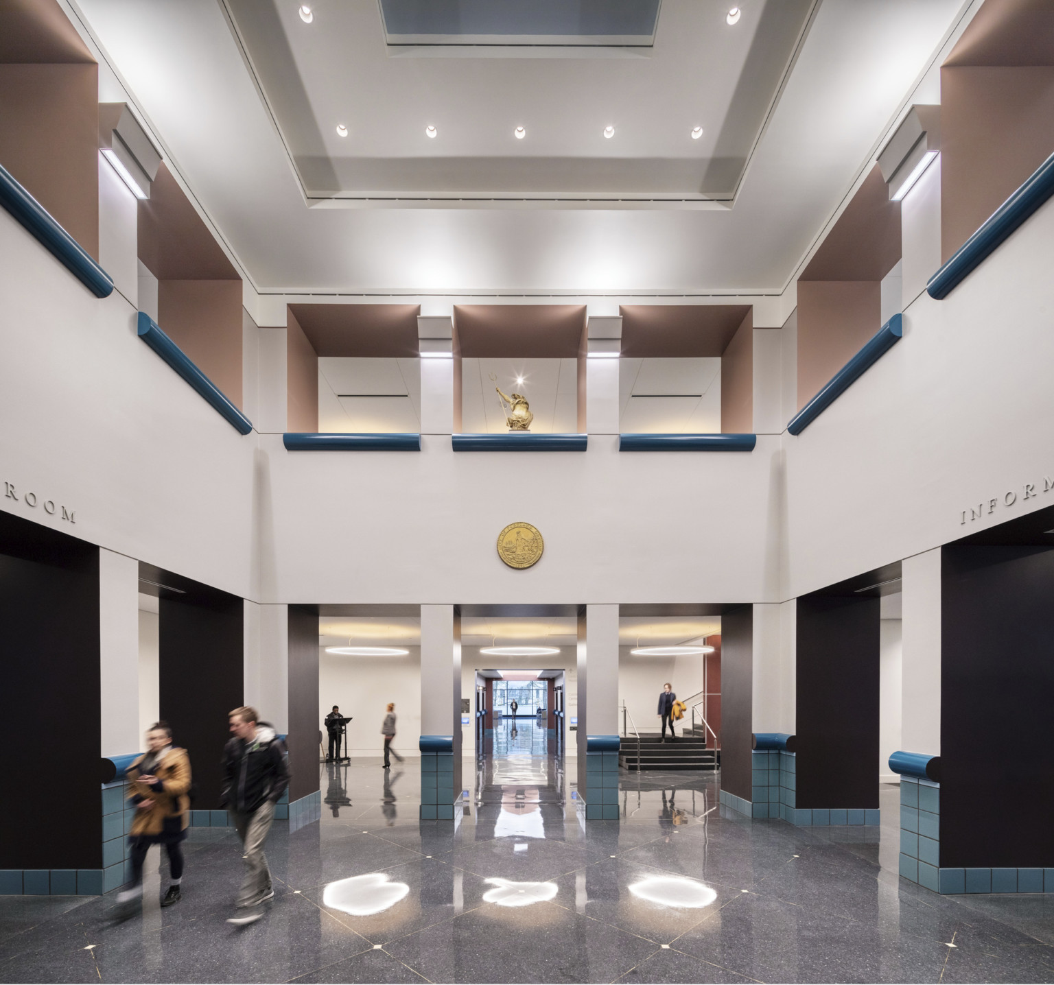 Lobby area at The Portland Building. Double height white atrium with interior balconies. Round gold accent on opposite wall