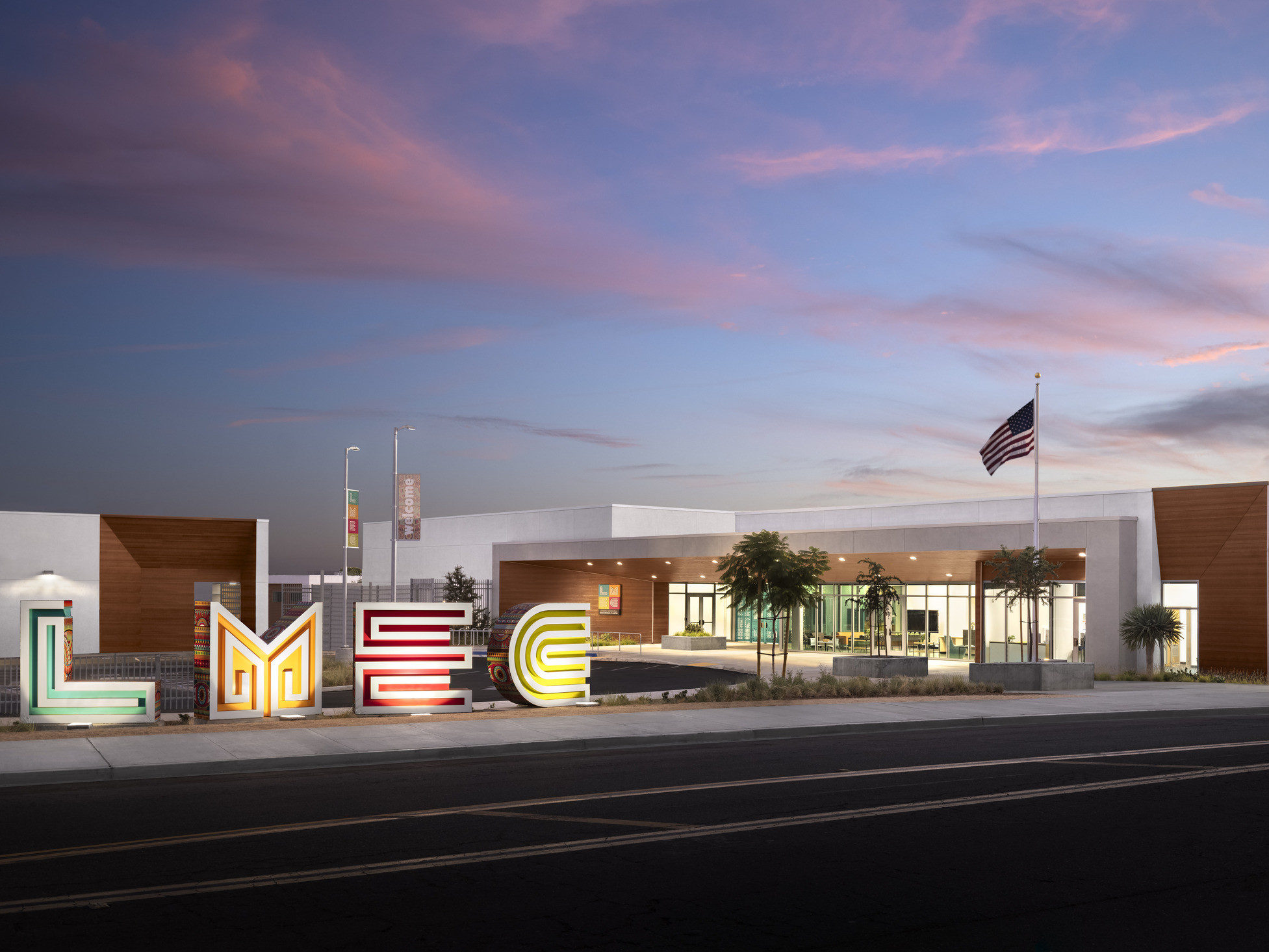 Logan Memorial Education Campus white and wood building viewed across the street; school design with sculpture abstracting the initials LMEC