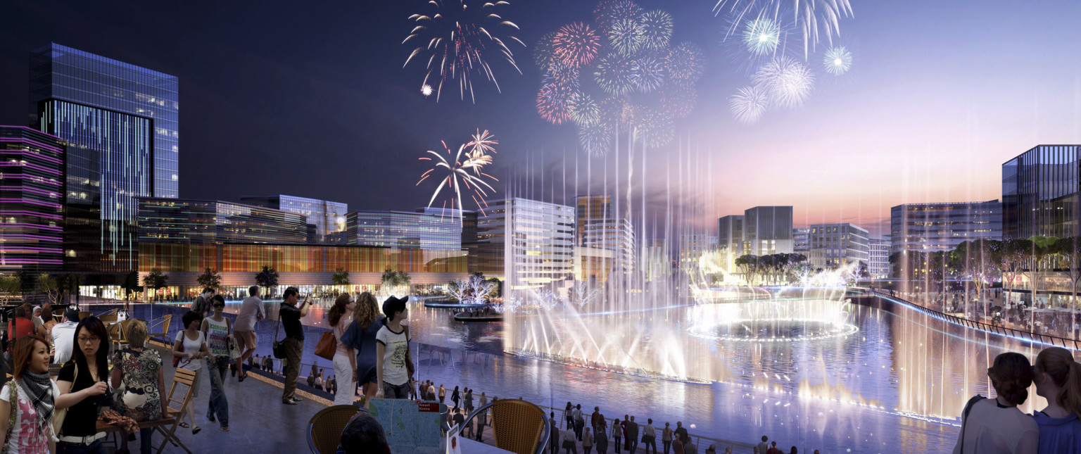 Tree lined lake with fountains surrounded by multistory glass buildings in the evening with fireworks overhead