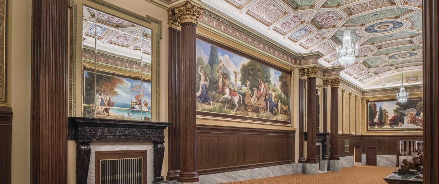 carpeted hallway with Corinthian columns and colorful ceiling frescoes and large scale wall murals