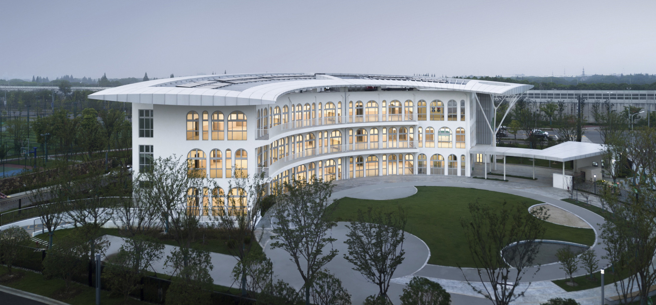 Suzhou Greenshore LOT 16 Kindergarten with semi circular facade and covered driveway to right. Arched windows line front, side