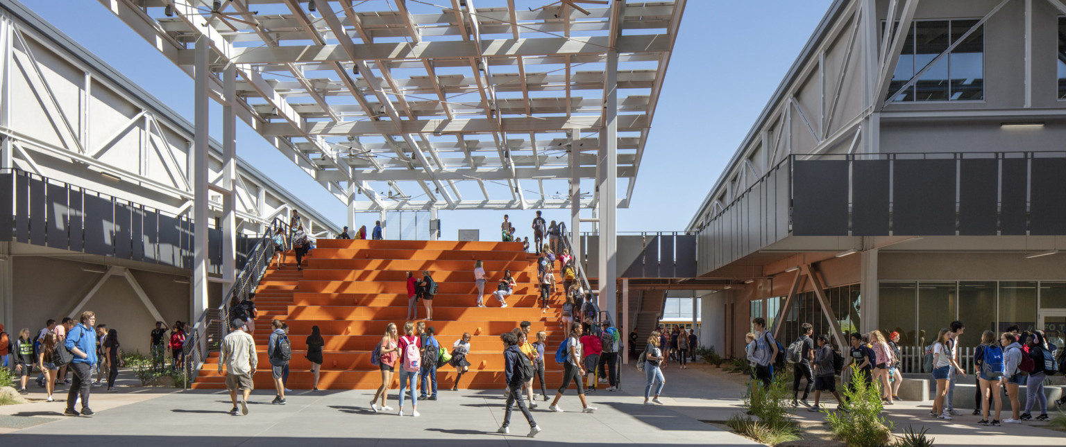 Looking out to students on orange bleacher steps partially cover by a solar canopy