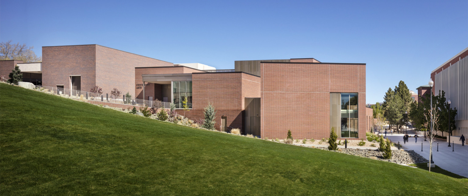 exterior view of the south elevation of the site with green grass covered hill in the forefront