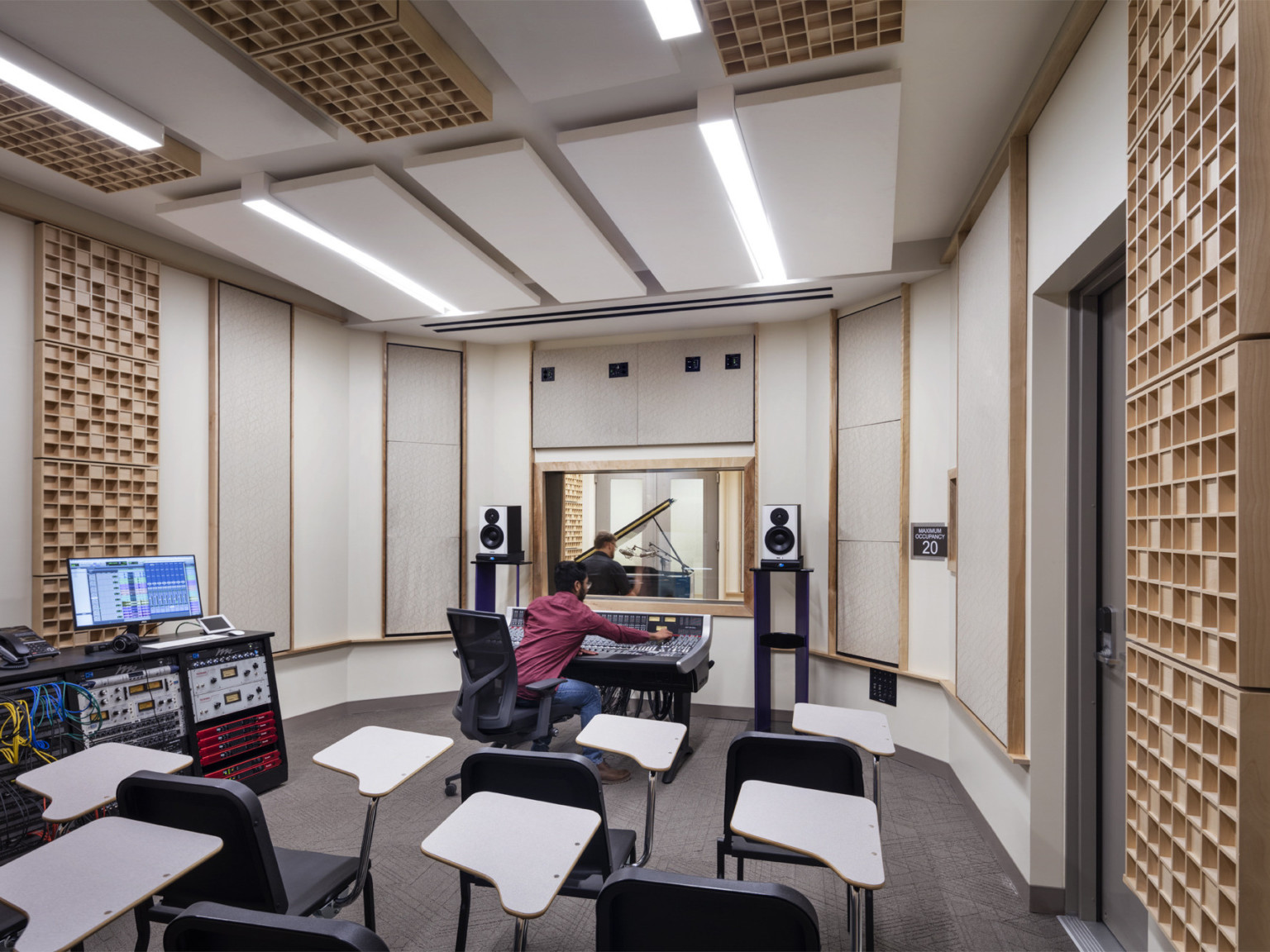 Student working in recording studio with white and wood panels on walls and ceiling