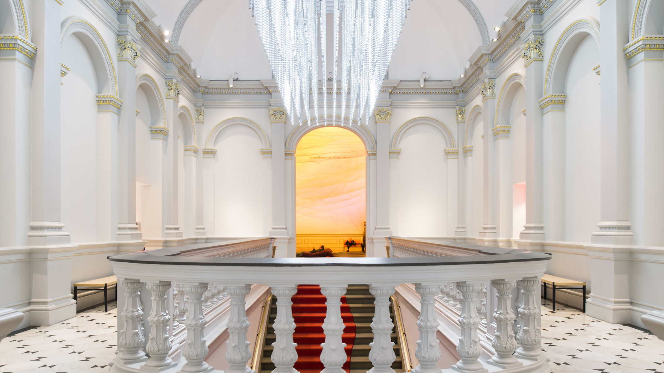 Custom sculptural chandelier hanging above staircase in white room at Renwick Gallery, banister with dark accent in front