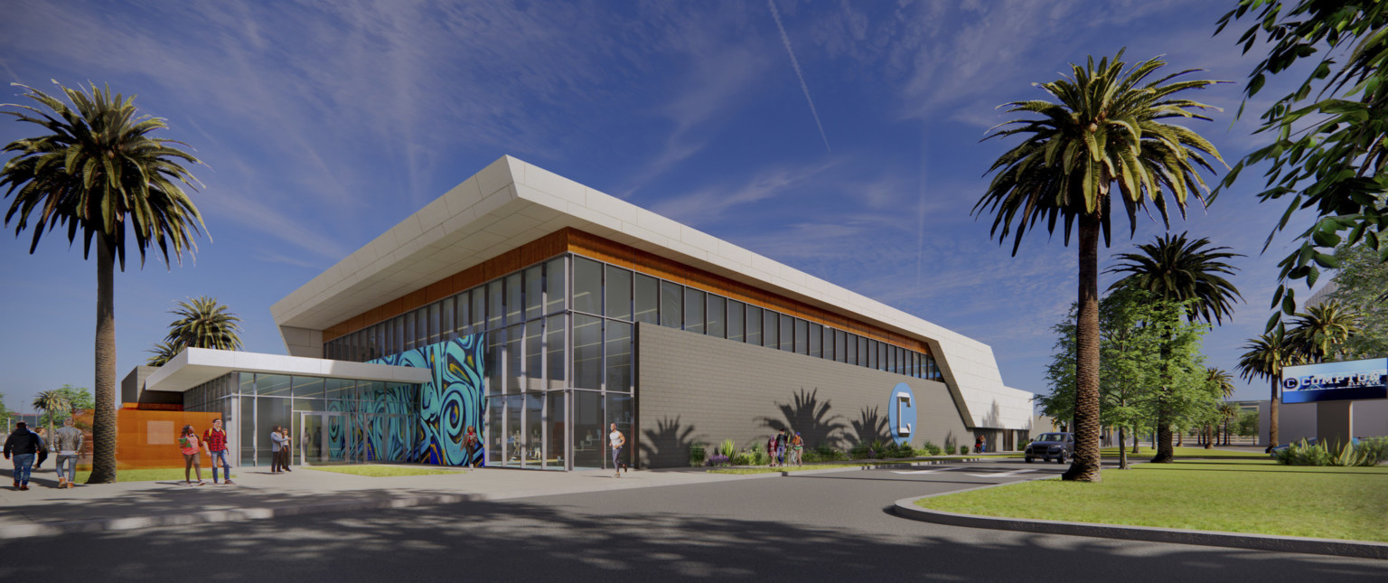 Building entry with double height windows and grey wrapping facade to right. White roof with overhang and wood details