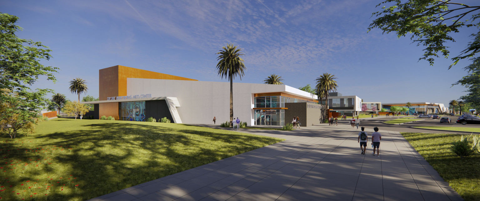 Corner view of building labeled Dr Dre Performing Arts Center. Angled white wrapped facade with brown details and mural left