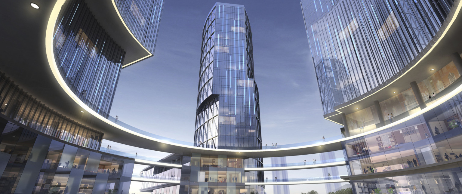 A round plaza with circular elevated walkway connecting 3 glass buildings at 3 stories. The side of walkways are illuminated