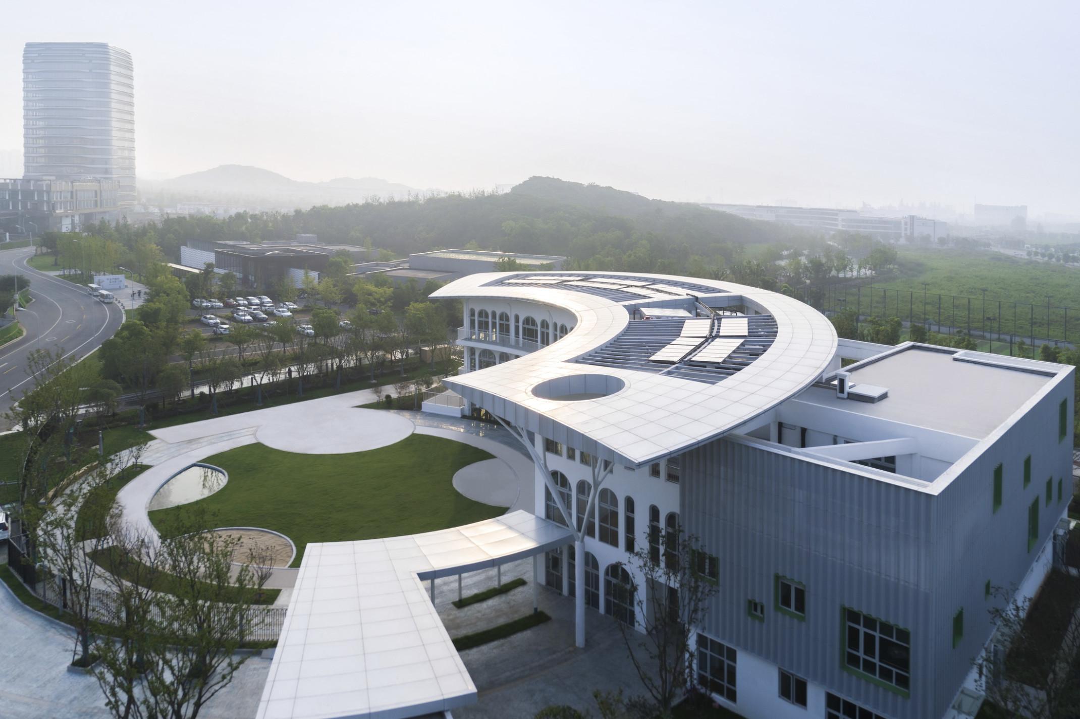 Suzhou Greenshore LOT 16 Kindergarten, a white 3 story building with semi circular canopy and front facade facing green lawn