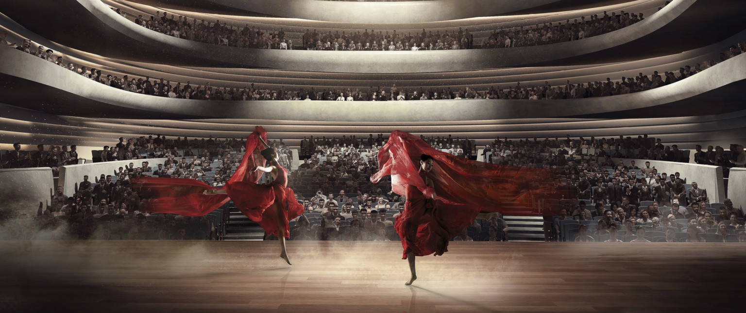 Upstage view of two dancers with red cloth lit from above center in front of audience at ground level and two balconies