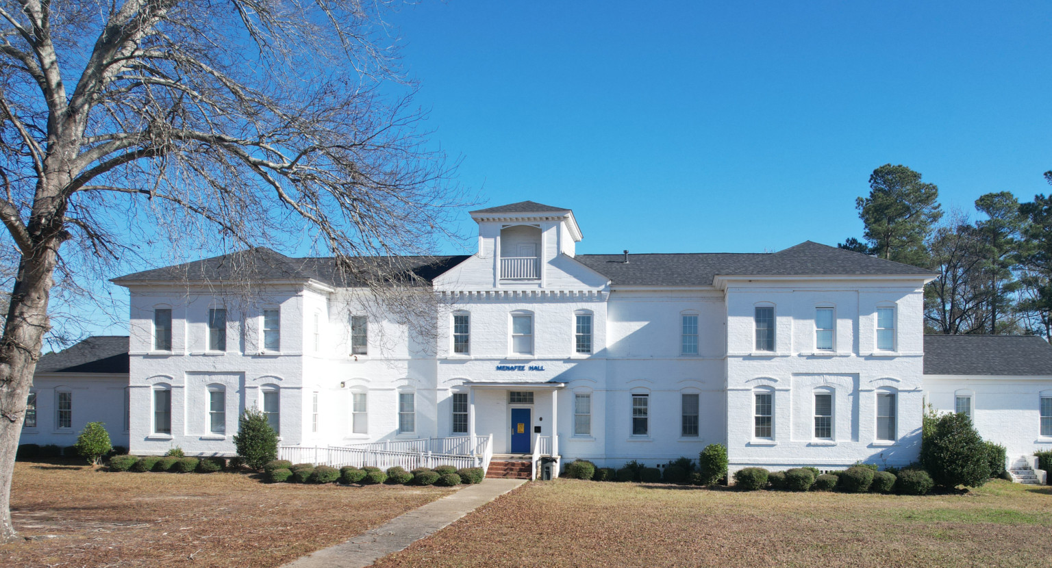 Menafee Hall at Voorhees College, an HBCU. A white 2 story building with central square turret and lookout over blue door