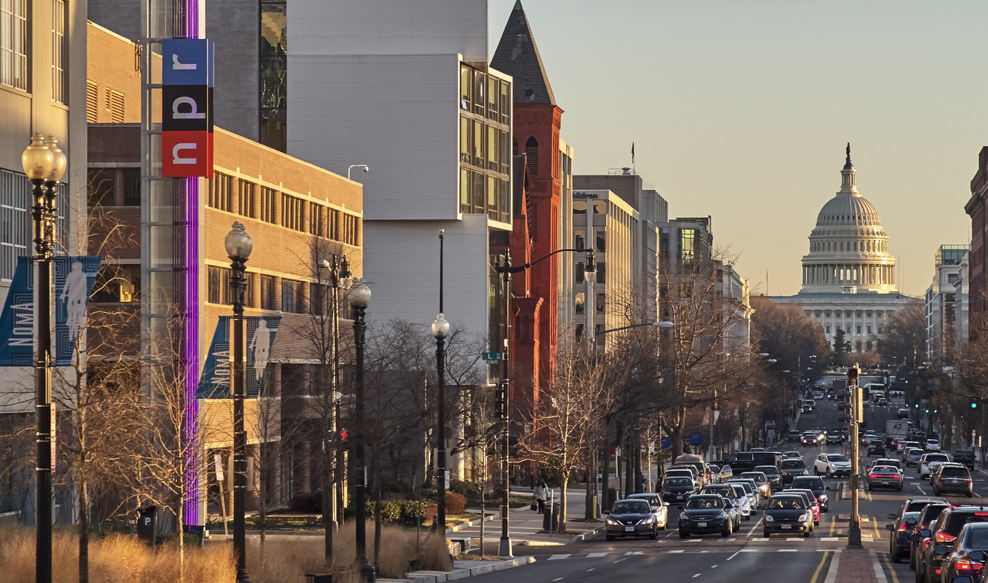 View down capital st to the capital dome full of vehicular and pedestrian traffic in washington dc against a sunset sky