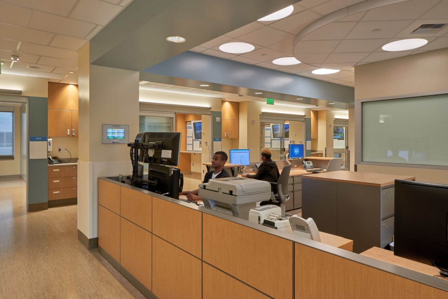 A wood panel desk in Swedish Issaquah Medical Center framed by the wall section and drop ceiling accent in corner workstation