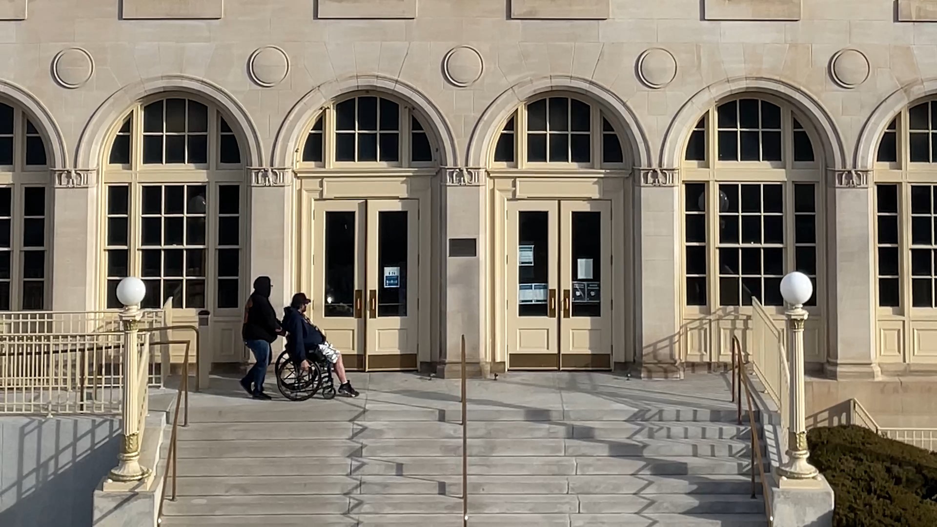 individual being pushed in a wheelchair outside a federal building, showing accessible design