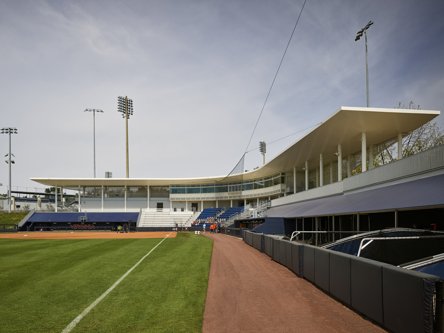 Field seen from 3rd base line to home. Virginia written across back of dugout to left. White canopy curves over back wall